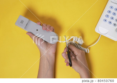 A man cuts a cable from the phone A man cuts a cable from the phone 80450760