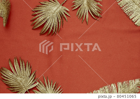 Decorative golden leaves on red textile backdrop 80451065