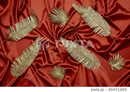Decorative golden leaves on red textile backdrop 80451860