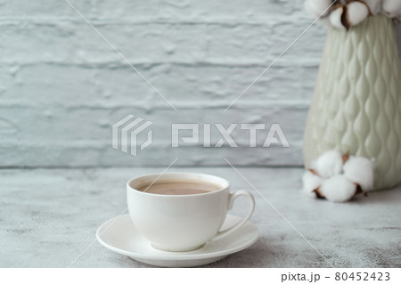 Cup of coffee with vase and cottons on rustic concrete background. Copy space. Home interior. Cup of coffee with vase and cottons on rustic concrete background. Copy space. Home interior. 80452423