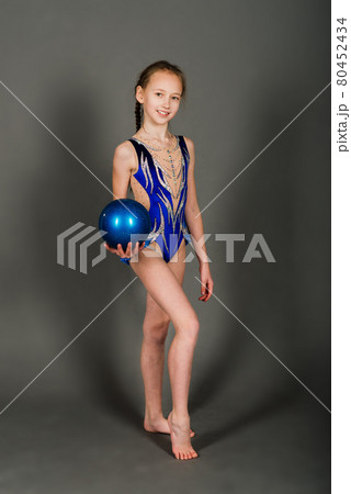 Little girl doing gymnastics with hoop, ball and split isolated on grey background 80452434