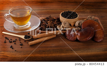 Tea, lingzhi, black pepper, cinnamon, star anise on wood 80454413