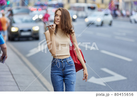 Woman in headphones talks by phone outdoors in summer. 80455656