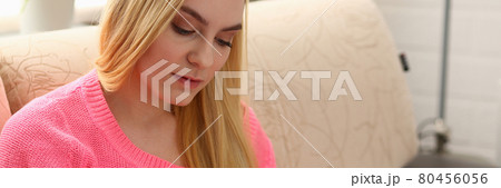 young beautiful blond woman sit on the sofa in livingroom hold binder in arms 80456056