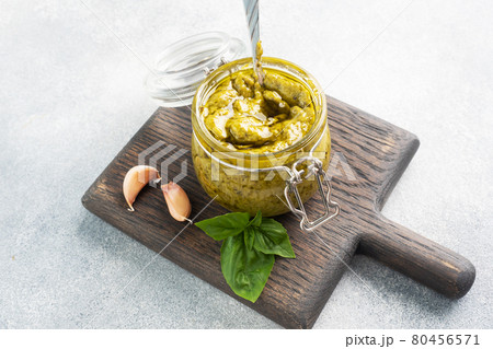 Pesto sauce in a glass jar, fresh basil leaves and garlic. copy space Pesto sauce in a glass jar, fresh basil leaves and garlic. copy space 80456571