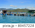 a floating fishing village in a sea bay, against a backdrop of mountains covered with tropical vegetation, clouds and a blue sky 80457228