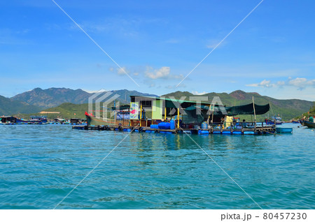 a floating fishing village in a sea bay, against a backdrop of mountains covered with tropical vegetation, clouds and a blue sky a floating fishing village in a sea bay, against a backdrop of mountains covered with tropical vegetation, clouds and a blue sky 80457230
