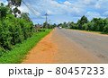 a provincial road, with buses traveling along it, people riding mopeds, against the backdrop of a bright green prastity, a blue sky covered with clouds 80457233
