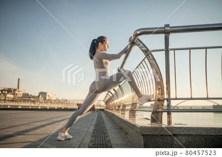 Young female sportsperson stretching her legs and doing lunges 80457523