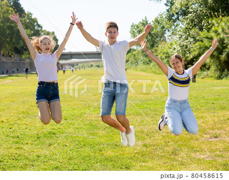 Happy teenagers jumping on the green lawn Happy teenagers jumping on the green lawn 80458615