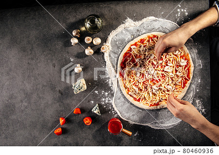 Making a pizza laying out the ham on the dough 80460936