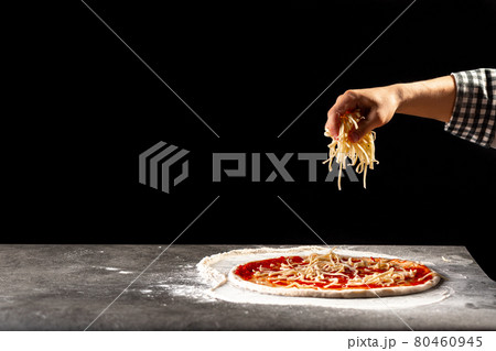 Making a pizza sprinkling dough with cheese 80460945