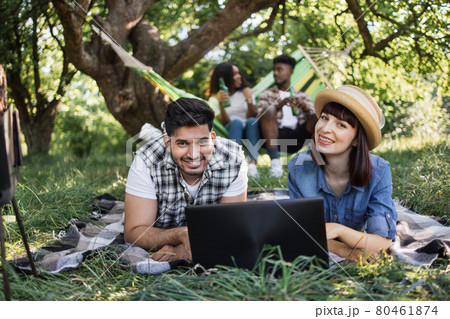 Four diverse friends using laptop on picnic at garden Four diverse friends using laptop on picnic at garden 80461874