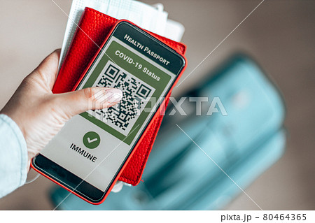 Young girl holding a passport, ticket pass and smartphone with digital health passport app for travel during covid-19 pandemic. Young girl holding a passport, ticket pass and smartphone with digital health passport app for travel during covid-19 pandemic. 80464365