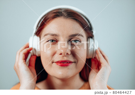 Beautiful joyful woman listen music dream close eyes white smile wear headphones isolated grey background 80464427