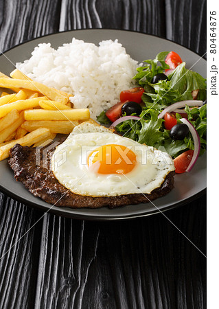 Bitoque is a classic Portuguese dish that is simply a steak drizzled with a butter pan sauce and topped with a fried egg closeup in the plate. Vertical 80464876