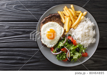Bitoque Recipe Portuguese Style Steak with Egg, french fries, rice and salad closeup in the plate. Horizontal top view 80464895