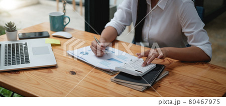 Close up asian female accountant or banker making calculations with calculator. Savings, finances and economy concept through a laptop Close up asian female accountant or banker making calculations with calculator. Savings, finances and economy concept through a laptop 80467975