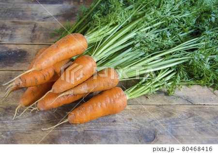 A bunch of carrots on a wooden table. 80468416