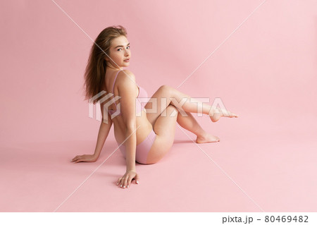Young beautiful adorable girl in nude color lingerie posing isolated over pink studio background. Natural beauty, spa, cosmetics, fitness and aesthetic cosmetology concept. 80469482