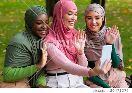 Muslim Ladies Making Video Call Using Phone Waving Hands Outdoors Muslim Ladies Making Video Call Using Phone Waving Hands Outdoors 80471272