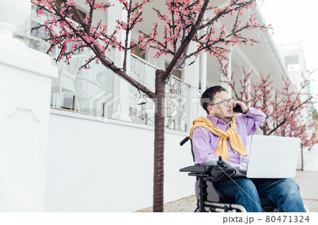 a man with disabilities in a wheelchair talking on a smartphone a man with disabilities in a wheelchair talking on a smartphone 80471324
