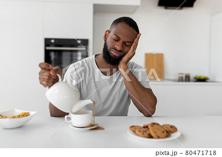Black man pouring coffee away from cup spilling hot drink Black man pouring coffee away from cup spilling hot drink 80471718