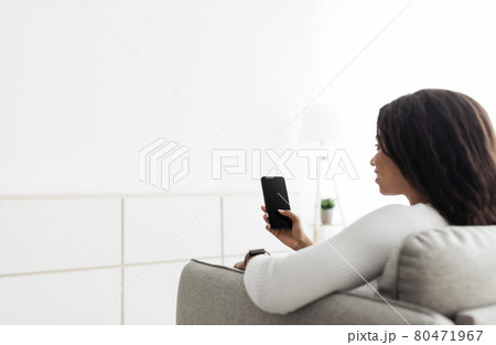 Home temperature, safety and control on mobile app. African american woman using smartphone, sitting on sofa, copy space Home temperature, safety and control on mobile app. African american woman using smartphone, sitting on sofa, copy space 80471967