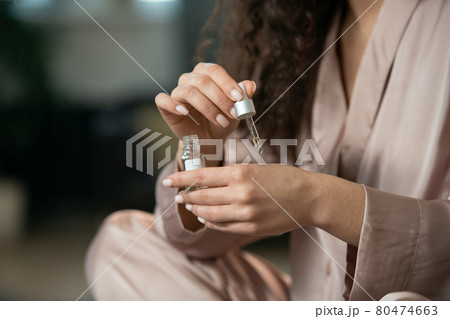 Young pleased woman in pajamas applying natural cosmetic product on her face Young pleased woman in pajamas applying natural cosmetic product on her face 80474663