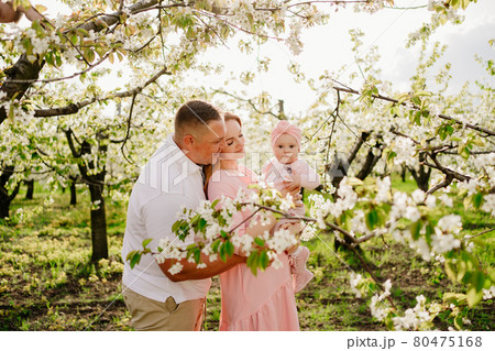 mom, dad and daughter in spring flowering garden. cleft lip in infants. 80475168