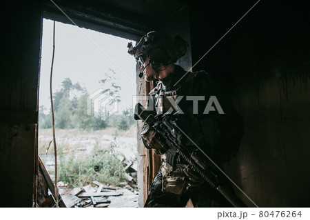 Military man with assault rifle standing inside building, he is ready for combat Military man with assault rifle standing inside building, he is ready for combat 80476264