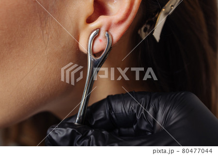 Professional holding the jewel of piercing just before screw the ball. Professional holding the jewel of piercing just before screw the ball. 80477044