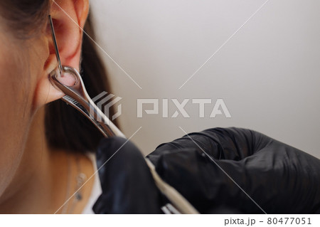 Professional holding the jewel of piercing just before screw the ball. Professional holding the jewel of piercing just before screw the ball. 80477051