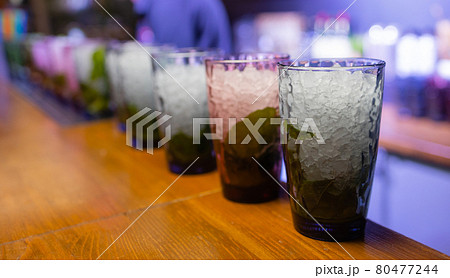 Bartender putting lime into glass. Muddling lime to make a cocktail. Barman holding glass. Bartender putting lime into glass. Muddling lime to make a cocktail. Barman holding glass. 80477244