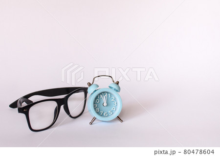 black glasses and a blue alarm clock shows 12 twelve o'clock. mock up black glasses and a blue alarm clock shows 12 twelve o'clock. mock up 80478604