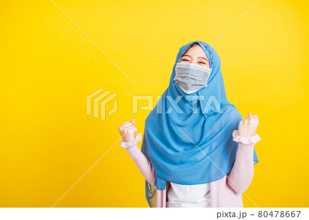 Asian Muslim Arab woman Islam wear veil hijab and face mask protect raise hands glad after recovering from illness Asian Muslim Arab woman Islam wear veil hijab and face mask protect raise hands glad after recovering from illness 80478667