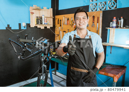 Portrait of a handsome repairman with thumbs up in an apron Portrait of a handsome repairman with thumbs up in an apron 80479941