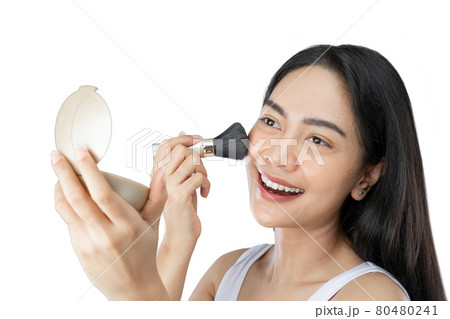 Beautiful young woman with long hair applying makeup using brush 80480241
