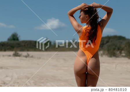 Graceful woman in orange swimsuit relaxing on beach Graceful woman in orange swimsuit relaxing on beach 80481010