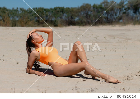 Attractive woman in sexy swimsuit relaxing on beach Attractive woman in sexy swimsuit relaxing on beach 80481014