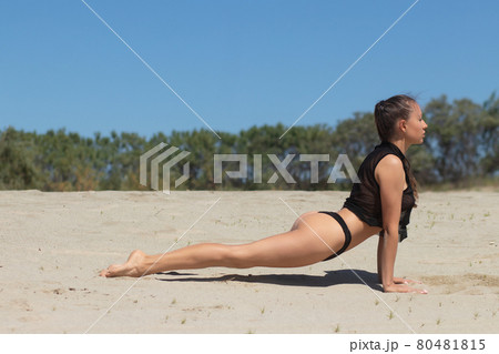 Graceful woman doing yoga pose on sandy beach Graceful woman doing yoga pose on sandy beach 80481815