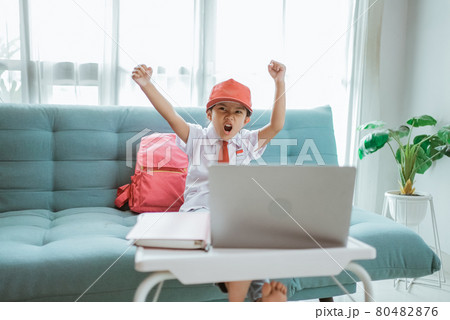 excited primary school student with uniform raise her arm during online class excited primary school student with uniform raise her arm during online class 80482876