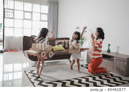 girl playing with cardboard toy airplane at home with mother girl playing with cardboard toy airplane at home with mother 80482877