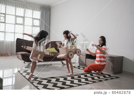 girl playing with cardboard toy airplane at home with mother girl playing with cardboard toy airplane at home with mother 80482878