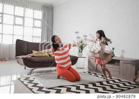 girl playing with cardboard toy airplane at home with mother girl playing with cardboard toy airplane at home with mother 80482879