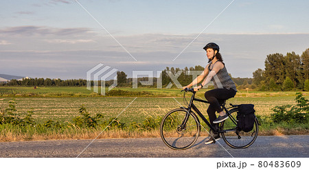 Adventurous White Cacasusian Woman riding a bicycle on a road. 80483609