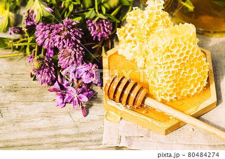 Fresh honeycomb lies on a wooden bowl plate on a summer rural background with herbs. Floral fragrant sweet honey dessert Fresh honeycomb lies on a wooden bowl plate on a summer rural background with herbs. Floral fragrant sweet honey dessert 80484274