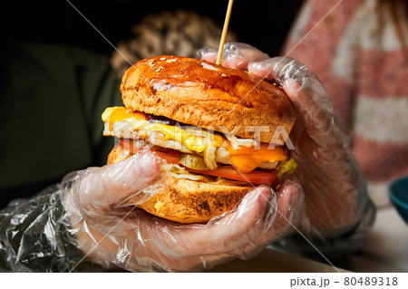 A boy holding a hamburger in his hands and getting ready to eat it. Close-up, selective focus 80489318