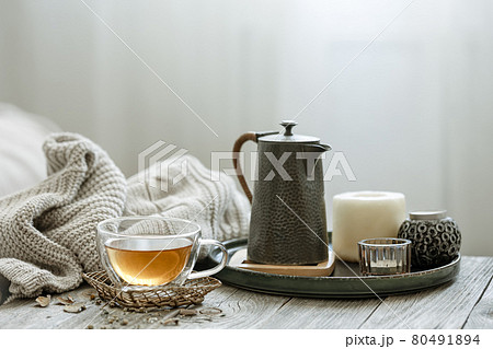 Home still life with a cup of tea, candles and a knitted element. 80491894