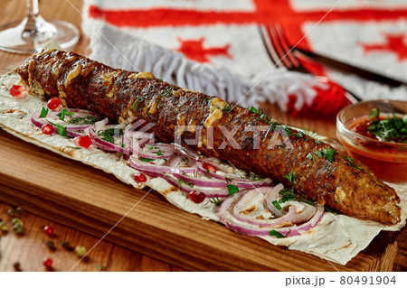 Beef and cheese kebab with lavash, onion, pomegranate seeds and satsebeli in Georgian restaurant 80491904